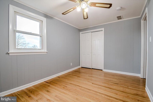 unfurnished bedroom with ceiling fan, a closet, crown molding, and light hardwood / wood-style floors