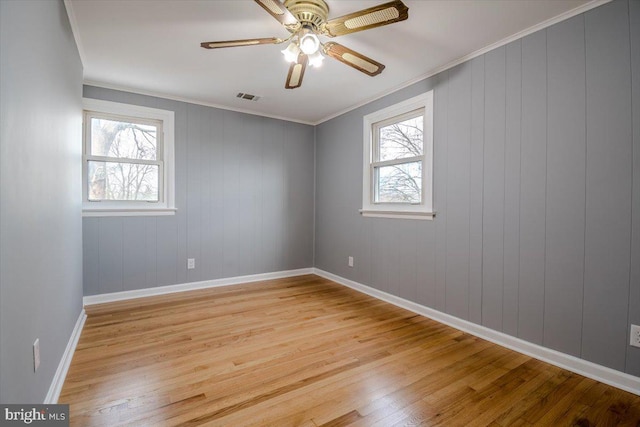 empty room with a healthy amount of sunlight, light hardwood / wood-style flooring, ceiling fan, and ornamental molding