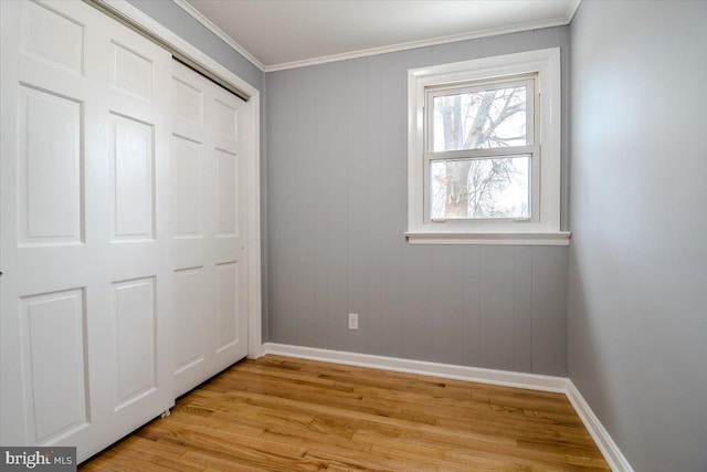 unfurnished bedroom featuring light hardwood / wood-style flooring, crown molding, and a closet