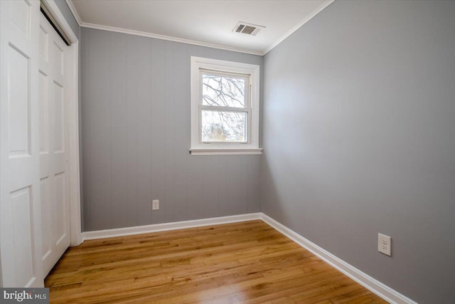 unfurnished bedroom featuring light wood-type flooring, a closet, and crown molding