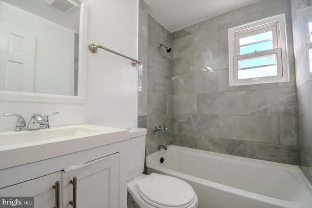 full bathroom featuring vanity, tiled shower / bath, and toilet