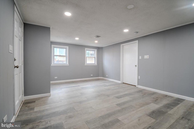 unfurnished room with light hardwood / wood-style floors, a textured ceiling, and ornamental molding