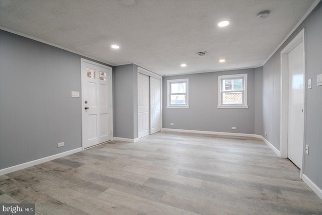 unfurnished room featuring light wood-type flooring and a textured ceiling