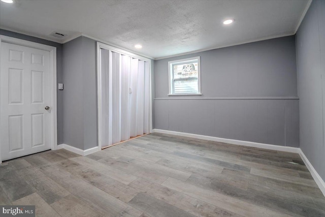 unfurnished room featuring light wood-type flooring and a textured ceiling