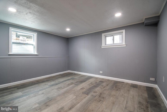 basement featuring hardwood / wood-style flooring, crown molding, and a textured ceiling