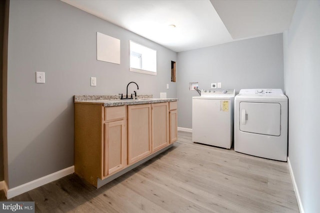 clothes washing area featuring washer and dryer, cabinets, sink, and light hardwood / wood-style flooring