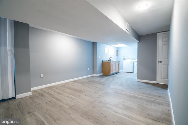 interior space with washing machine and dryer and light hardwood / wood-style flooring