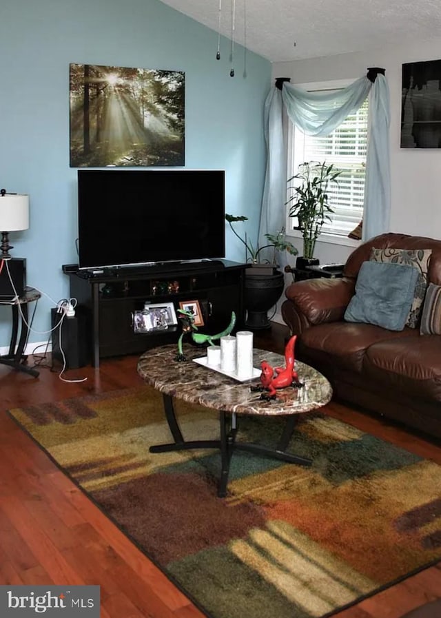 living room with a textured ceiling, hardwood / wood-style flooring, and vaulted ceiling