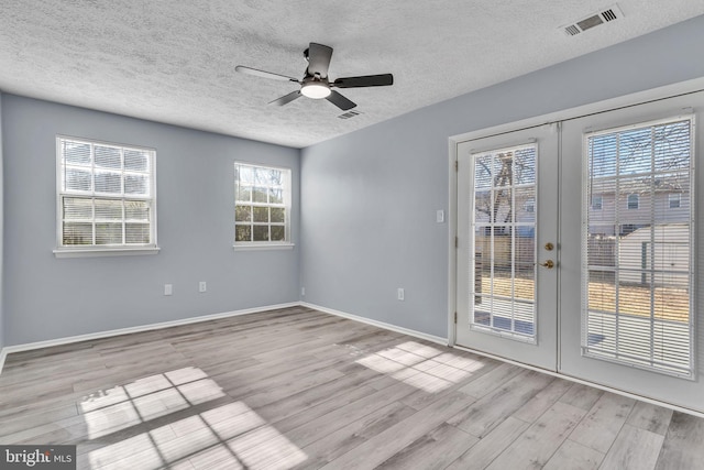 unfurnished room with baseboards, visible vents, ceiling fan, wood finished floors, and french doors