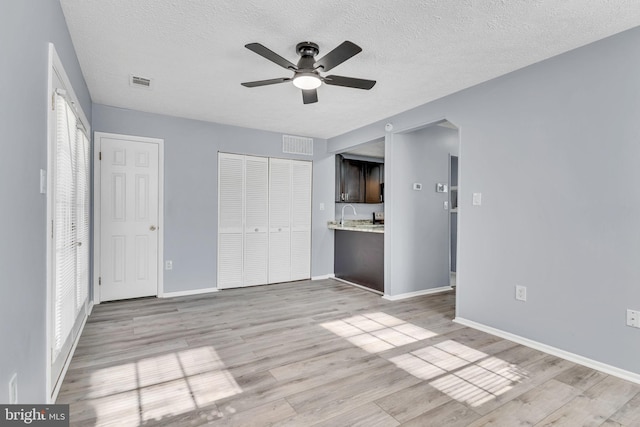 unfurnished bedroom featuring baseboards, visible vents, light wood-style flooring, and a textured ceiling