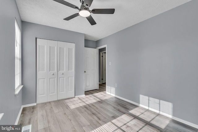 unfurnished bedroom with a closet, wood finished floors, visible vents, and baseboards