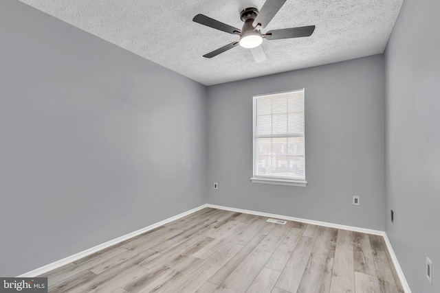 spare room featuring visible vents, a textured ceiling, baseboards, and wood finished floors