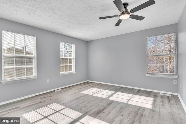 empty room with a textured ceiling, baseboards, and wood finished floors