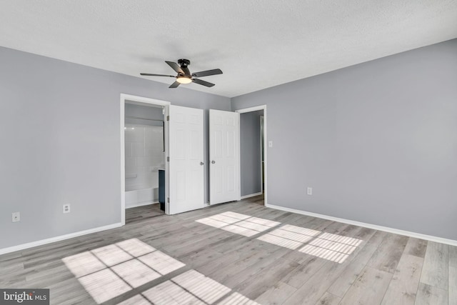 unfurnished bedroom with a textured ceiling, baseboards, and wood finished floors