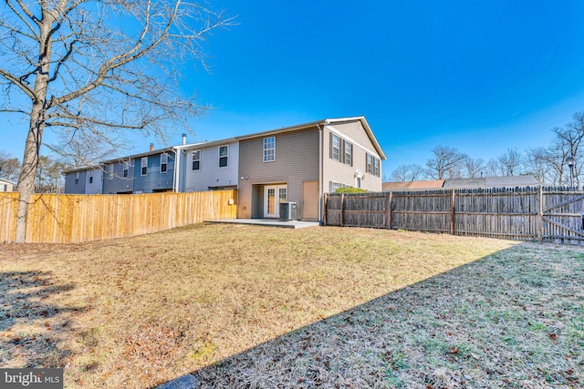 rear view of house with central air condition unit, a fenced backyard, and a lawn