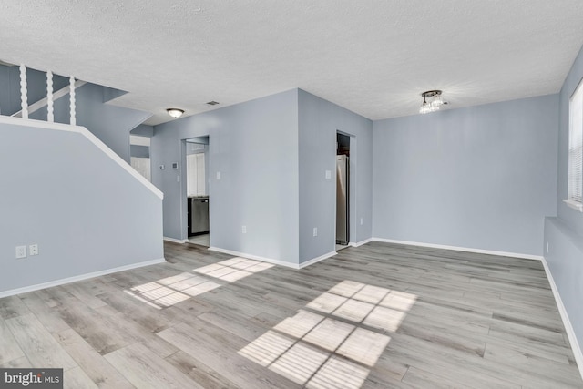 unfurnished living room featuring visible vents, a textured ceiling, baseboards, and wood finished floors