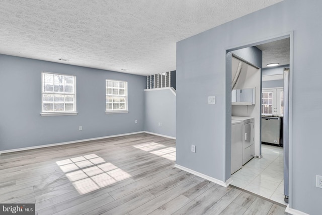 spare room with a textured ceiling, visible vents, baseboards, light wood-style floors, and washer and dryer