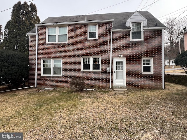 back of house featuring brick siding and a yard