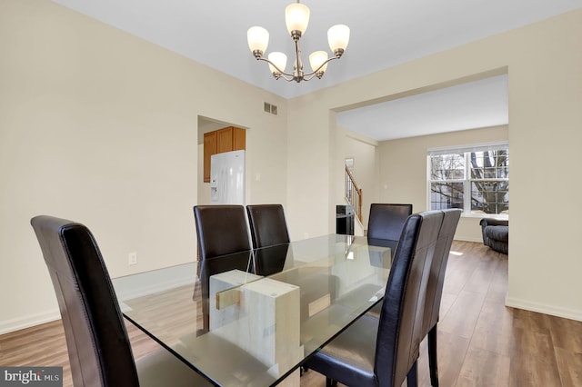 dining area with an inviting chandelier, baseboards, visible vents, and wood finished floors