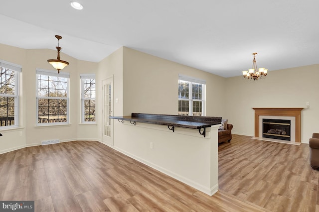 kitchen featuring dark countertops, light wood-type flooring, a kitchen breakfast bar, and a wealth of natural light