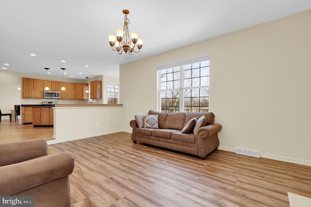 living room with light wood-style flooring, recessed lighting, visible vents, baseboards, and an inviting chandelier