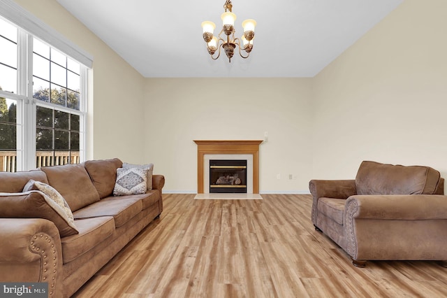 living room featuring baseboards, an inviting chandelier, a fireplace with flush hearth, and light wood-style floors