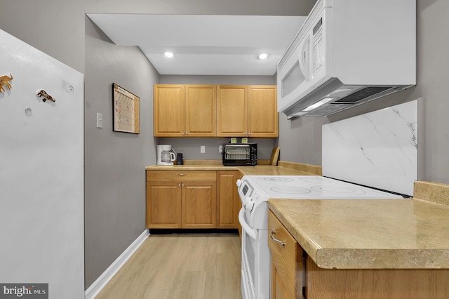 kitchen featuring white appliances, light wood finished floors, baseboards, light countertops, and recessed lighting