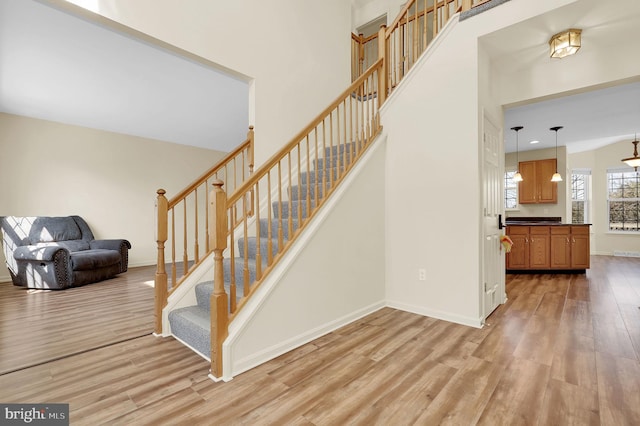 stairway with a high ceiling, baseboards, and wood finished floors