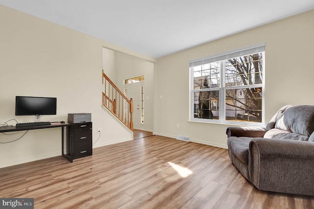 interior space featuring stairs, light wood-type flooring, visible vents, and baseboards