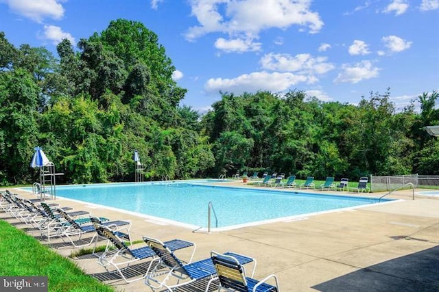 pool with a patio area and fence