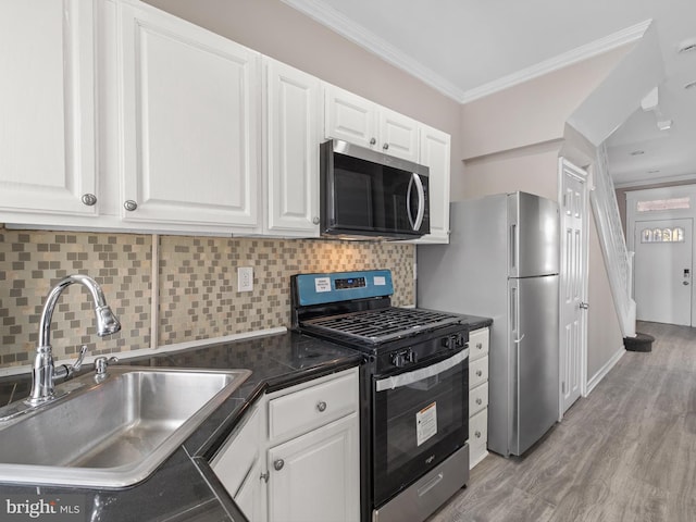 kitchen featuring stainless steel appliances, dark countertops, white cabinetry, and a sink