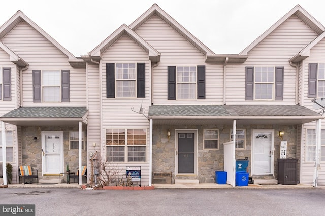 multi unit property featuring a shingled roof and stone siding