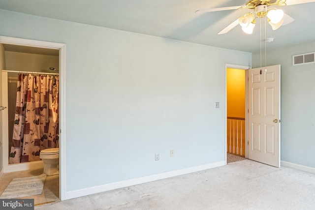 unfurnished bedroom with baseboards, visible vents, light colored carpet, ceiling fan, and ensuite bathroom