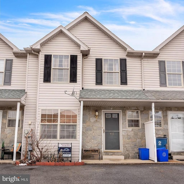 multi unit property featuring stone siding and a shingled roof