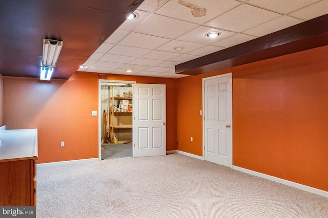 finished basement featuring carpet, a paneled ceiling, and baseboards