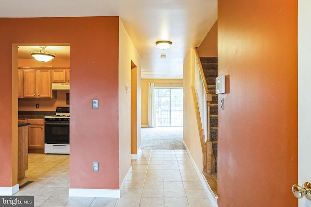 corridor featuring baseboards, visible vents, stairway, and light tile patterned flooring