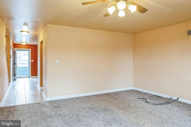 spare room featuring light tile patterned floors, light colored carpet, a ceiling fan, baseboards, and visible vents