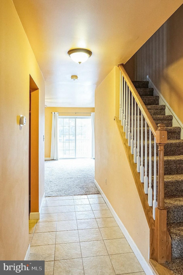 hall with stairs, light tile patterned flooring, and baseboards