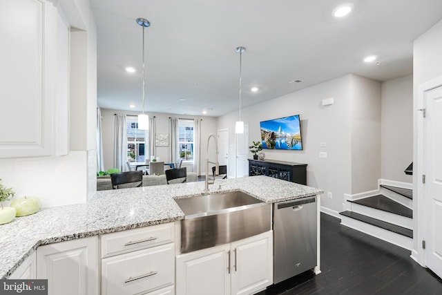 kitchen with hanging light fixtures, white cabinets, a sink, light stone countertops, and dishwasher