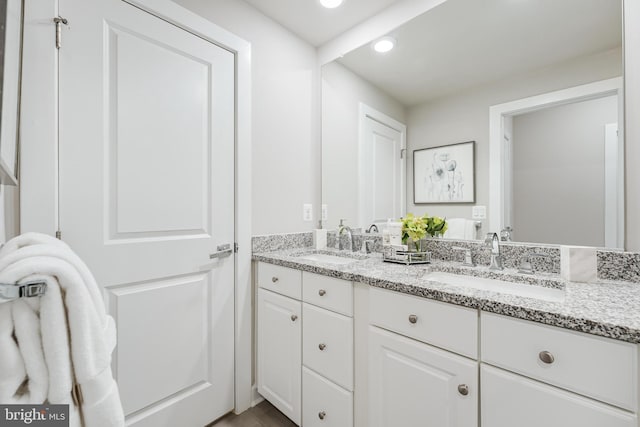 bathroom with double vanity, a sink, and recessed lighting