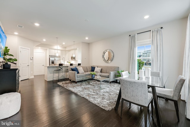 living room with dark wood finished floors, visible vents, and recessed lighting