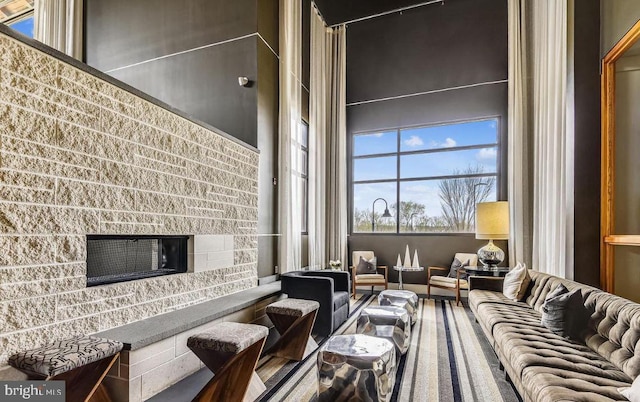 living room featuring a high ceiling and a fireplace with raised hearth