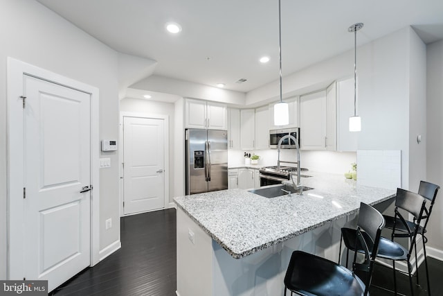 kitchen with decorative light fixtures, stainless steel appliances, white cabinetry, a peninsula, and a kitchen bar