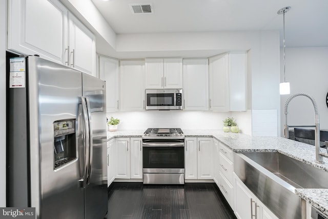 kitchen featuring stainless steel appliances, a sink, visible vents, white cabinetry, and pendant lighting