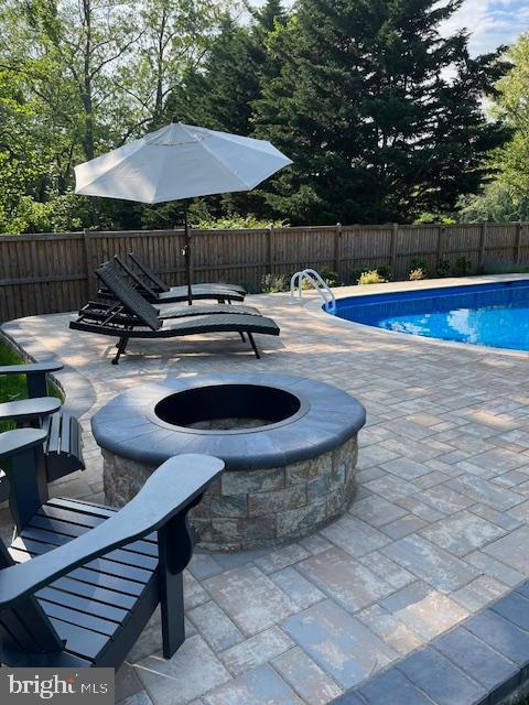 view of swimming pool featuring a fenced backyard, a fenced in pool, a patio, and a fire pit