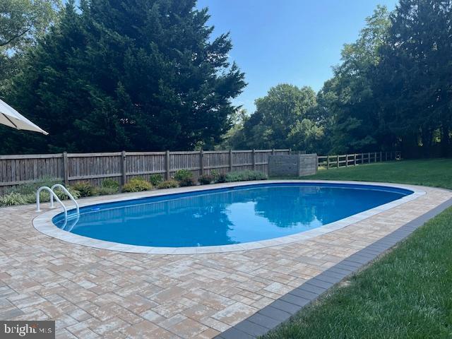 view of swimming pool featuring a fenced in pool, a patio, a yard, and a fenced backyard