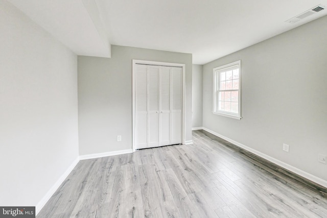 unfurnished bedroom with light wood-type flooring and a closet