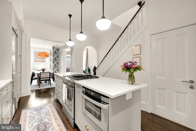 kitchen featuring arched walkways, light countertops, appliances with stainless steel finishes, a center island, and pendant lighting