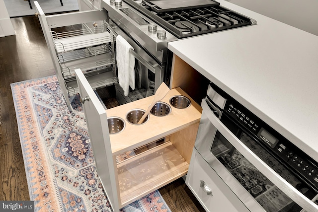 kitchen with white cabinetry, light countertops, dark wood finished floors, and gas stove