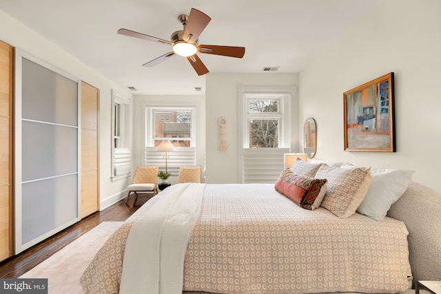 bedroom featuring a ceiling fan, visible vents, and dark wood-style flooring